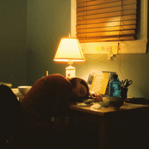 Personne assoupie devant un ordinateur dans un bureau en désordre, illustrant la fatigue numérique et la surcharge administrative que vivent de nombreuses associations. Article sur la dispersion des outils, la charge mentale et des solutions pour simplifier l’organisation.