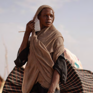 Femme dans un contexte humanitaire tenant un tissu sur la tête, illustrant la résilience des populations locales dans les crises humanitaires